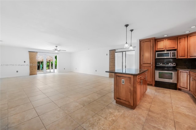 kitchen with light tile patterned floors, appliances with stainless steel finishes, hanging light fixtures, backsplash, and a center island