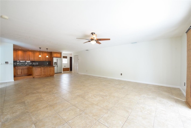 unfurnished living room featuring ceiling fan and baseboards