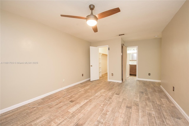 unfurnished bedroom with light wood-style flooring, a spacious closet, visible vents, and baseboards