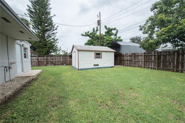 view of yard with a fenced backyard, a storage unit, and an outdoor structure