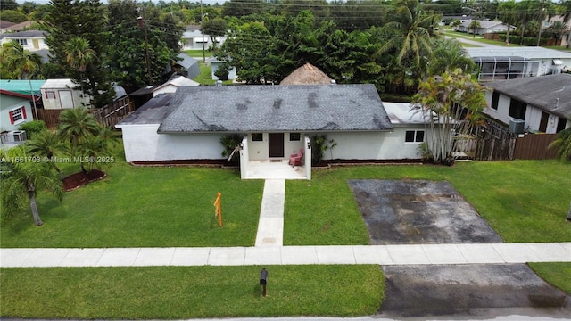 view of front facade featuring aphalt driveway, fence, a front lawn, and stucco siding