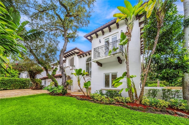 back of house with a balcony and a lawn