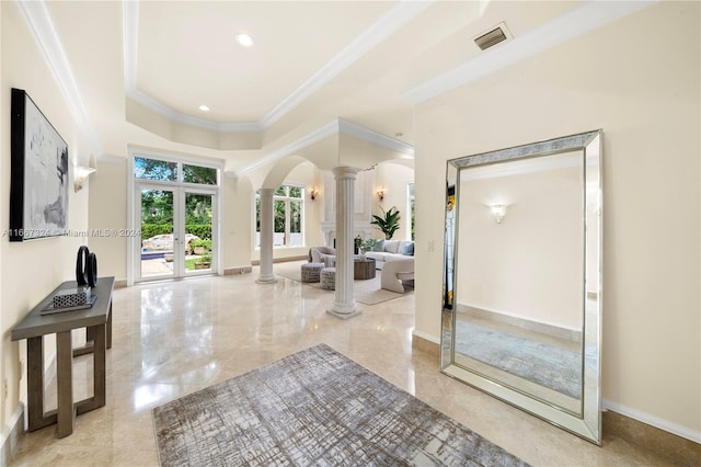 interior space with a raised ceiling, ornamental molding, french doors, and ornate columns