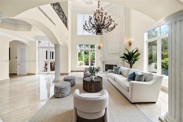 living room with decorative columns, crown molding, a high ceiling, and a wealth of natural light