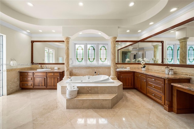 bathroom featuring ornate columns, vanity, and a relaxing tiled tub