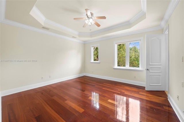 unfurnished bedroom featuring ornamental molding, a tray ceiling, dark hardwood / wood-style floors, and ceiling fan