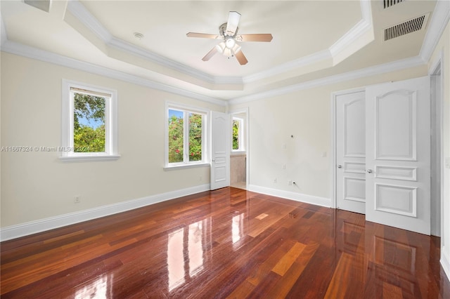 unfurnished bedroom with ceiling fan, a tray ceiling, ornamental molding, and dark hardwood / wood-style flooring