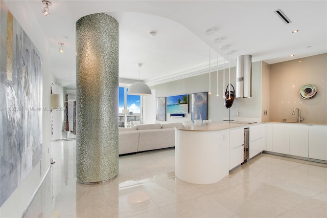 kitchen with kitchen peninsula, white cabinetry, sink, and decorative light fixtures