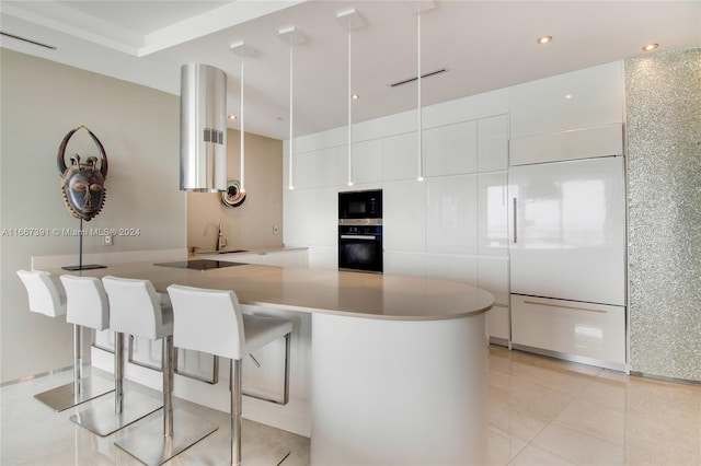 kitchen with a kitchen breakfast bar, kitchen peninsula, paneled built in refrigerator, and white cabinetry