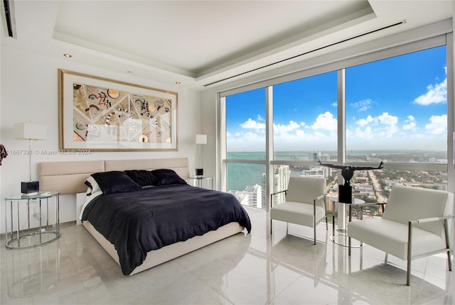 bedroom featuring a water view, a raised ceiling, and tile patterned floors