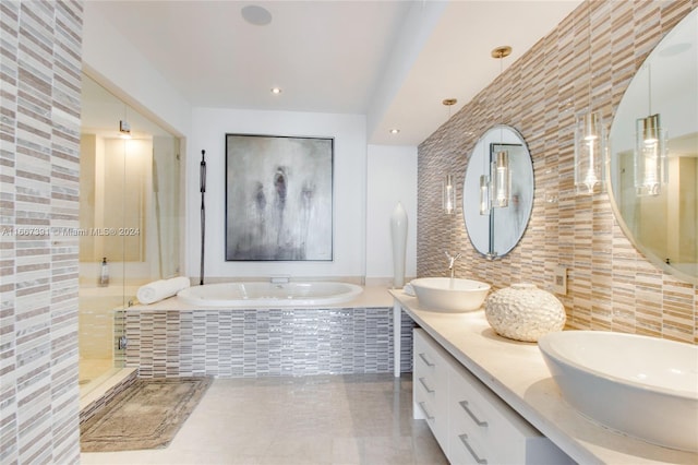 bathroom with decorative backsplash, tile walls, vanity, and separate shower and tub