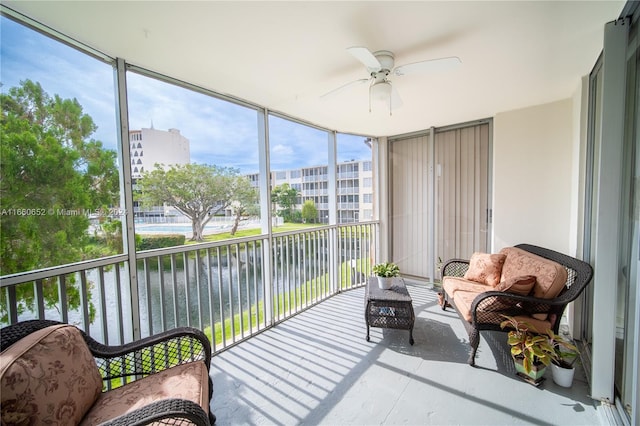 sunroom featuring a water view and ceiling fan