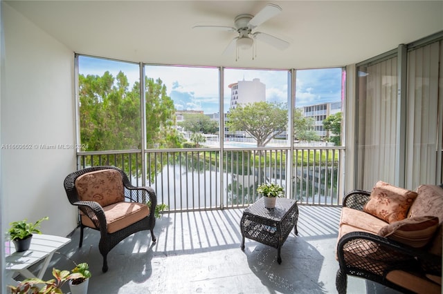 sunroom / solarium featuring ceiling fan and a water view