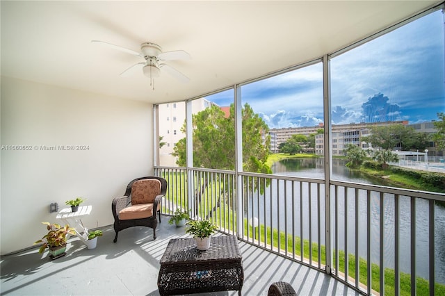 sunroom featuring ceiling fan and a water view