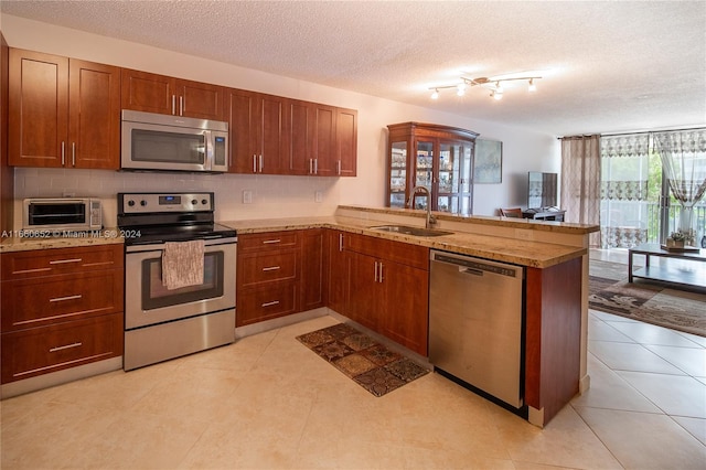 kitchen with appliances with stainless steel finishes, kitchen peninsula, and sink