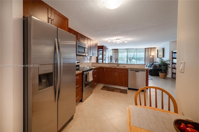 kitchen with sink, appliances with stainless steel finishes, kitchen peninsula, and a textured ceiling