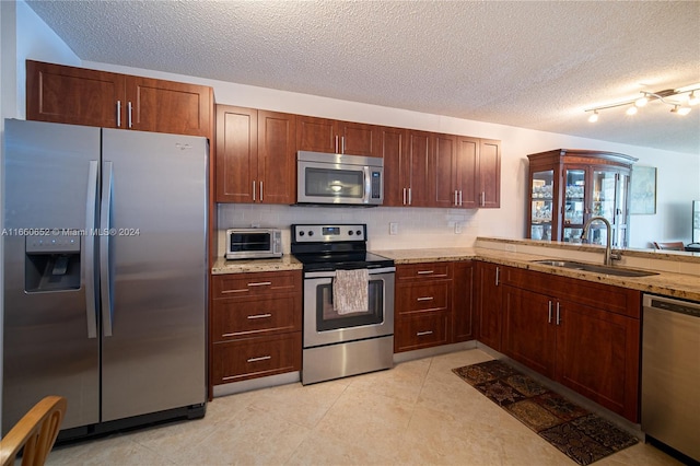 kitchen featuring light stone counters, sink, tasteful backsplash, a textured ceiling, and stainless steel appliances