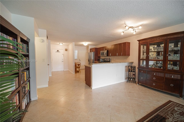 kitchen featuring appliances with stainless steel finishes, a textured ceiling, kitchen peninsula, and light tile patterned floors