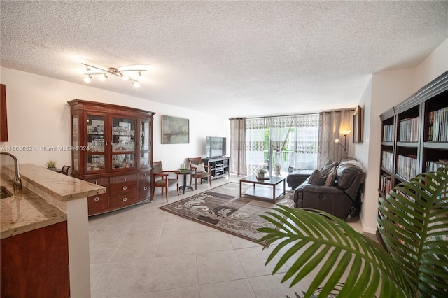 tiled living room featuring a textured ceiling and rail lighting