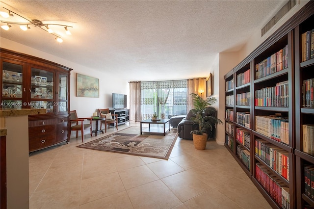 sitting room featuring a textured ceiling, light tile patterned floors, and rail lighting