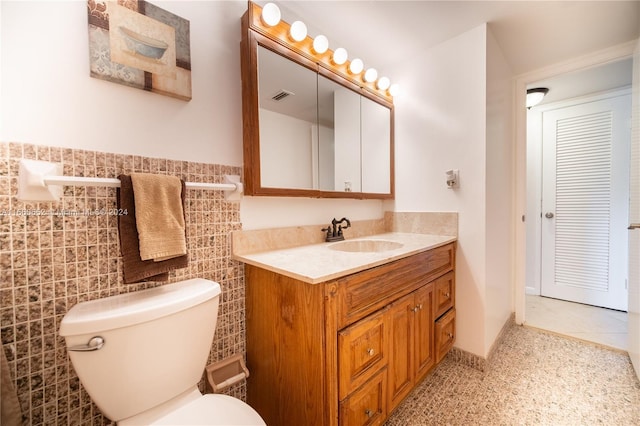 bathroom with vanity, tile walls, and toilet