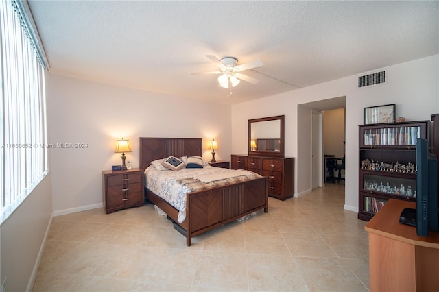 bedroom with ceiling fan, a textured ceiling, and light tile patterned flooring