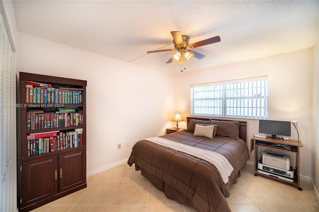 bedroom featuring a textured ceiling, light tile patterned flooring, and ceiling fan