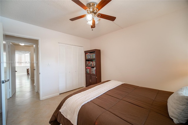 tiled bedroom with ceiling fan, a textured ceiling, and a closet