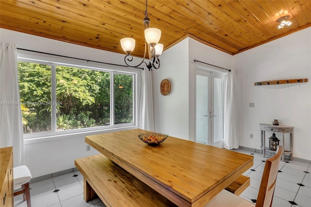 tiled dining space with wood ceiling, ornamental molding, an inviting chandelier, and french doors