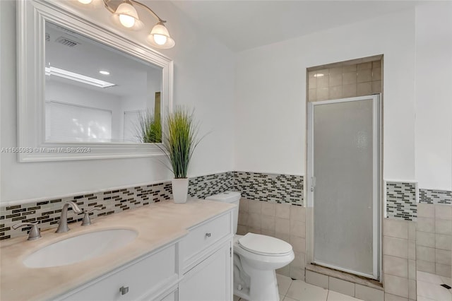 bathroom featuring vanity, tile patterned floors, tile walls, toilet, and a shower with door