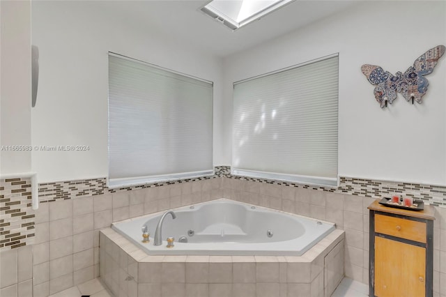 bathroom with tile patterned floors, a skylight, and a relaxing tiled tub