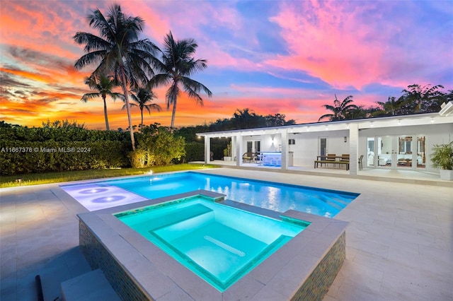 pool at dusk with french doors, a patio, and an in ground hot tub