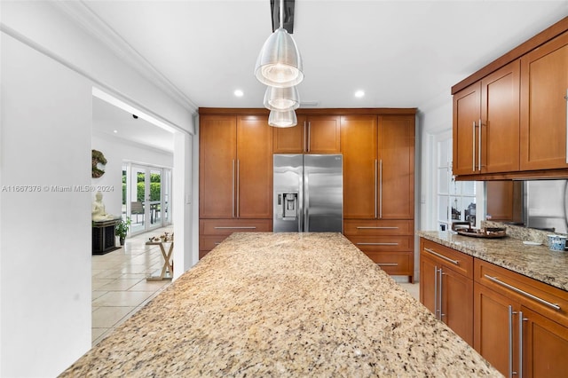 kitchen with light tile patterned flooring, stainless steel fridge, pendant lighting, light stone counters, and ornamental molding