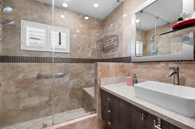 bathroom featuring tile walls, vanity, and a shower with shower door