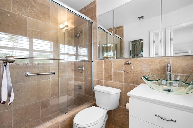 bathroom with vanity, walk in shower, toilet, and tile walls