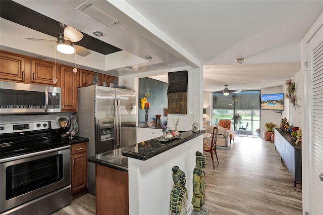 kitchen with light hardwood / wood-style flooring, kitchen peninsula, ceiling fan, and appliances with stainless steel finishes