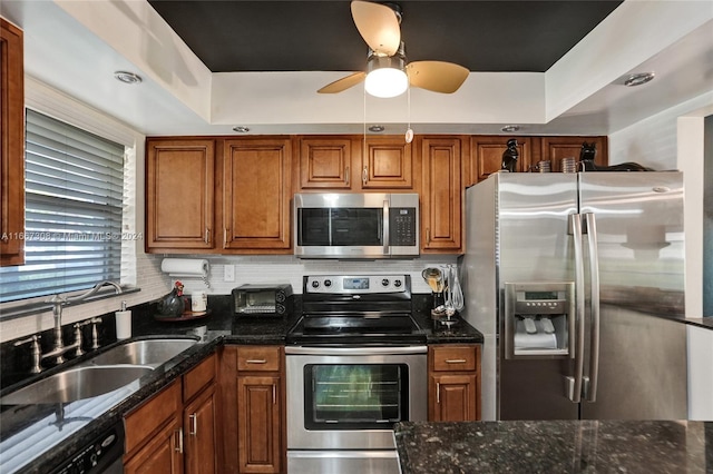 kitchen with ceiling fan, sink, appliances with stainless steel finishes, and a tray ceiling