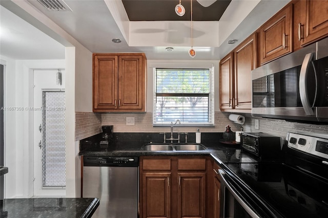 kitchen with appliances with stainless steel finishes, decorative backsplash, a tray ceiling, and sink