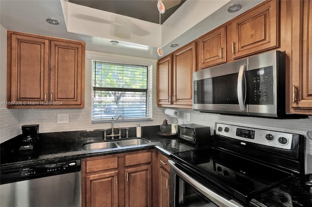 kitchen with dark stone countertops, backsplash, appliances with stainless steel finishes, and sink