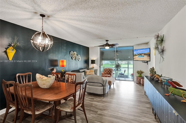 dining space featuring hardwood / wood-style flooring, ceiling fan with notable chandelier, and a textured ceiling