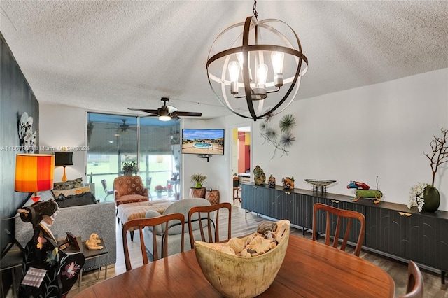 dining room with ceiling fan with notable chandelier, a textured ceiling, and hardwood / wood-style flooring