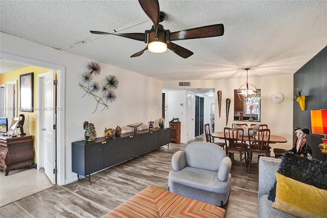 living room featuring a textured ceiling, ceiling fan with notable chandelier, and hardwood / wood-style flooring