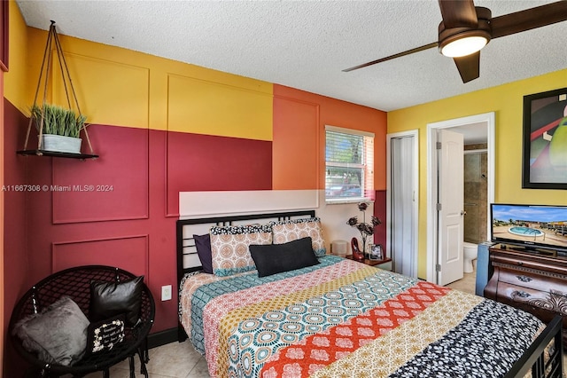 bedroom featuring a textured ceiling, light tile patterned floors, connected bathroom, and ceiling fan