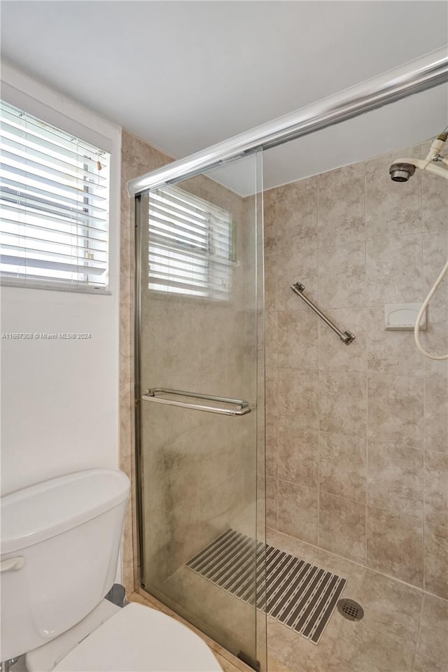 bathroom with toilet and a shower with door