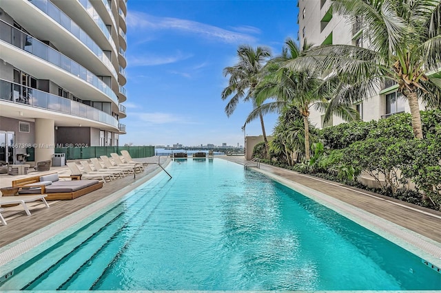 view of pool featuring cooling unit and a water view