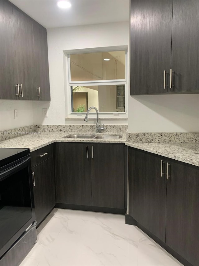 kitchen with dark brown cabinetry, light stone countertops, black range with electric cooktop, and sink