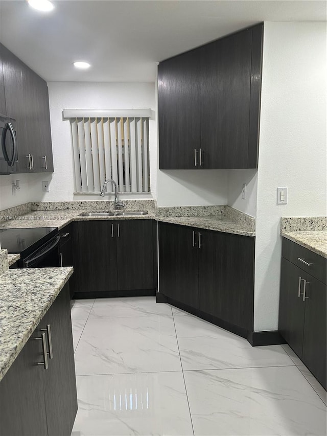 kitchen with light stone counters, black / electric stove, and sink