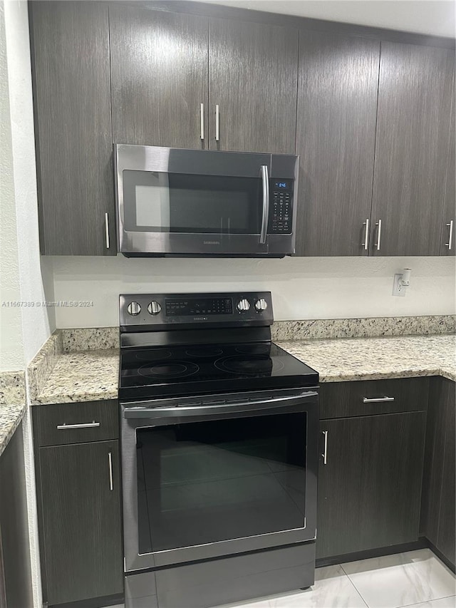 kitchen with dark brown cabinets, stainless steel appliances, and light stone counters