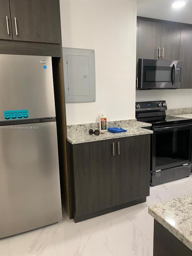 kitchen with stainless steel appliances, light stone counters, electric panel, and dark brown cabinetry