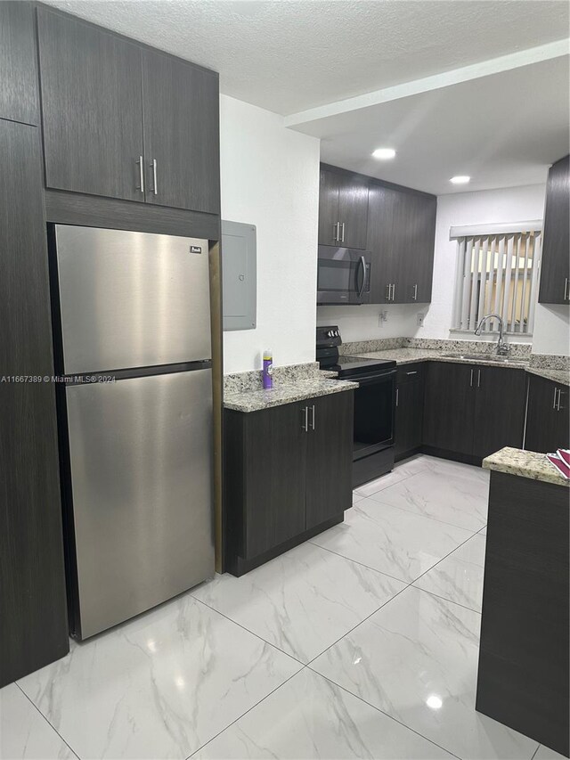 kitchen with light stone countertops, a textured ceiling, stainless steel appliances, and sink